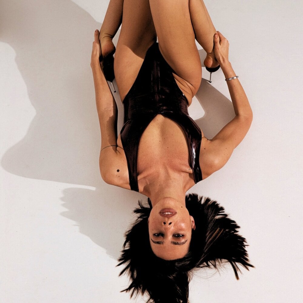 ANOESES-Body aus schwarzem, glänzendem Latex mit durchgehendem Frontreißverschluss und V-Ausschnitt.