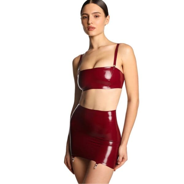 Short skirt in shiny burgundy latex with criss-cross lacing at back and garter belt fastenings.