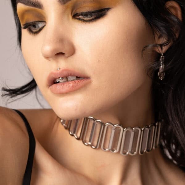 Modelo que lleva el Bulletproof Gargantilla Cristal Perlensau con base transparente y placas articuladas de metal plateado, ofrecido por Brigade Mondaine Paris.