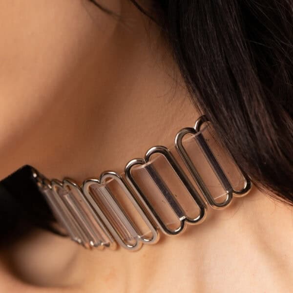 Modelo que lleva el Bulletproof Gargantilla Cristal Perlensau con base transparente y placas articuladas de metal plateado, ofrecido por Brigade Mondaine Paris.