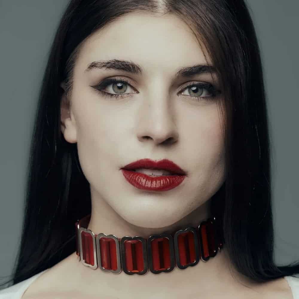 Modell, das den roten Bulletproof Choker von Perlensau mit durchscheinenden roten Platten und Metallstruktur trägt, angeboten von Brigade Mondaine Paris.