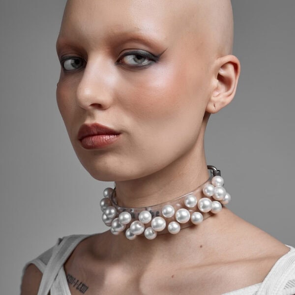 Modell trägt Boudoir Choker Perlensau mit weißen Perlen, die auf einer transparenten Basis montiert sind, angeboten von Brigade Mondaine Paris.