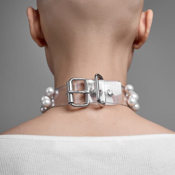 Modell trägt Boudoir Choker Perlensau mit weißen Perlen, die auf einer transparenten Basis montiert sind, angeboten von Brigade Mondaine Paris.