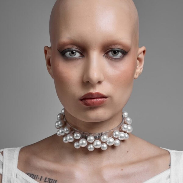 Modell trägt Boudoir Choker Perlensau mit weißen Perlen, die auf einer transparenten Basis montiert sind, angeboten von Brigade Mondaine Paris.