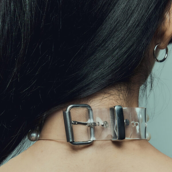 Modell trägt Boudoir Choker Perlensau mit weißen Perlen, die auf einer transparenten Basis montiert sind, angeboten von Brigade Mondaine Paris.