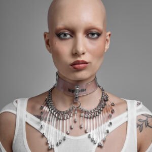 Modèle portant le Cosmic Choker Perlensau en matière transparente avec chaînes métalliques et pampilles suspendues, proposé par Brigade Mondaine Paris.