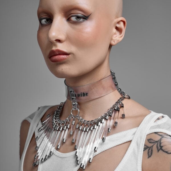 Modelo que lleva el Cosmic Choker Perlensau en material transparente con cadenas de metal y colgantes, ofrecido por Brigade Mondaine Paris.