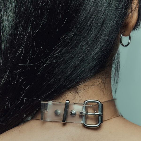 Modelo que lleva el Cosmic Choker Perlensau en material transparente con cadenas de metal y colgantes, ofrecido por Brigade Mondaine Paris.