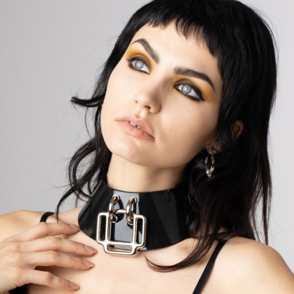 Model wearing glossy black Phenomenon Choker Perlensau with large geometric metal buckle, offered by Brigade Mondaine Paris.