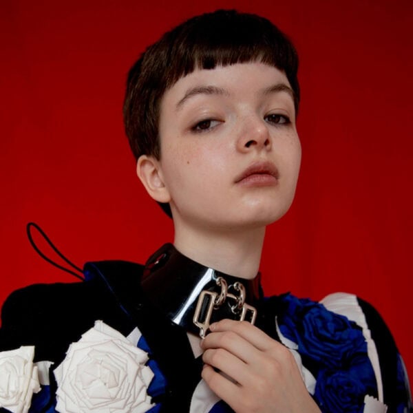 Model wearing glossy black Phenomenon Choker Perlensau with large geometric metal buckle, offered by Brigade Mondaine Paris.