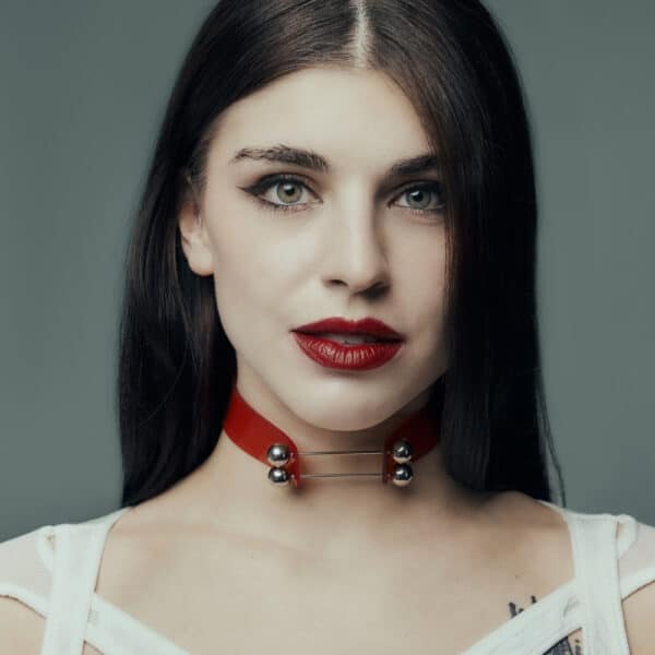 На модели красный чокер Perlensau Industrial Choker из кожи с металлическими шипами и серебряными сферами, предложенный Brigade Mondaine Paris.