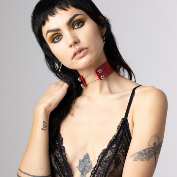 На модели красный чокер Perlensau Industrial Choker из кожи с металлическими шипами и серебряными сферами, предложенный Brigade Mondaine Paris.