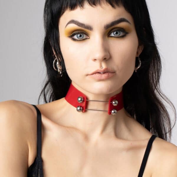 На модели красный чокер Perlensau Industrial Choker из кожи с металлическими шипами и серебряными сферами, предложенный Brigade Mondaine Paris.