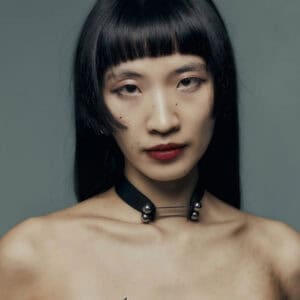 Modèle portant le Industrial Choker Perlensau en cuir noir avec éléments métalliques argentés, proposé par Brigade Mondaine Paris.