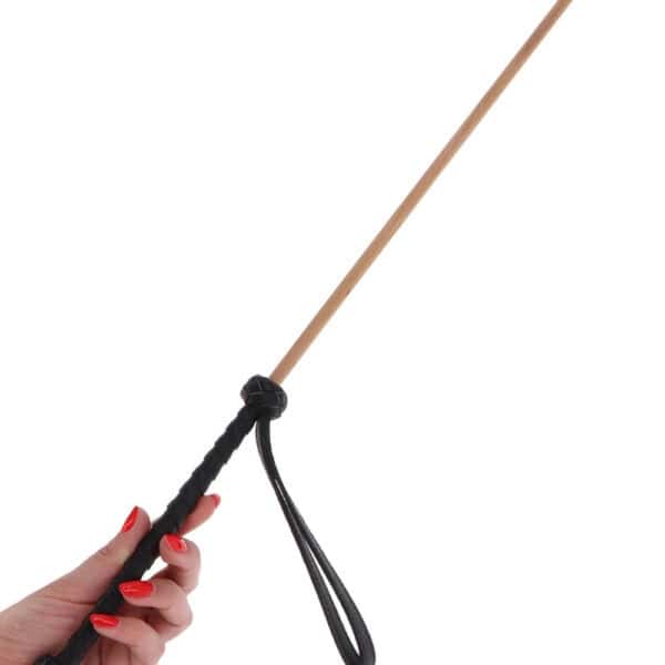 Bastón Obediance de madera clara con empuñadura de cuero negro y correa de mano a juego, accesorio ofrecido por Brigade Mondaine Paris.