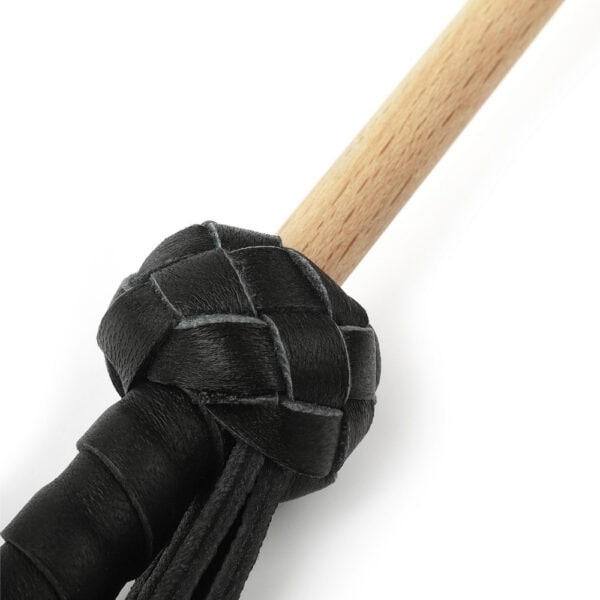 Bastón Obediance de madera clara con empuñadura de cuero negro y correa de mano a juego, accesorio ofrecido por Brigade Mondaine Paris.
