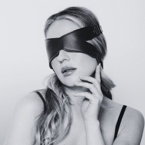 X-band de cuero negro con correas ajustables y hebillas de metal, accesorio bondage ofrecido por Brigade Mondaine Paris.