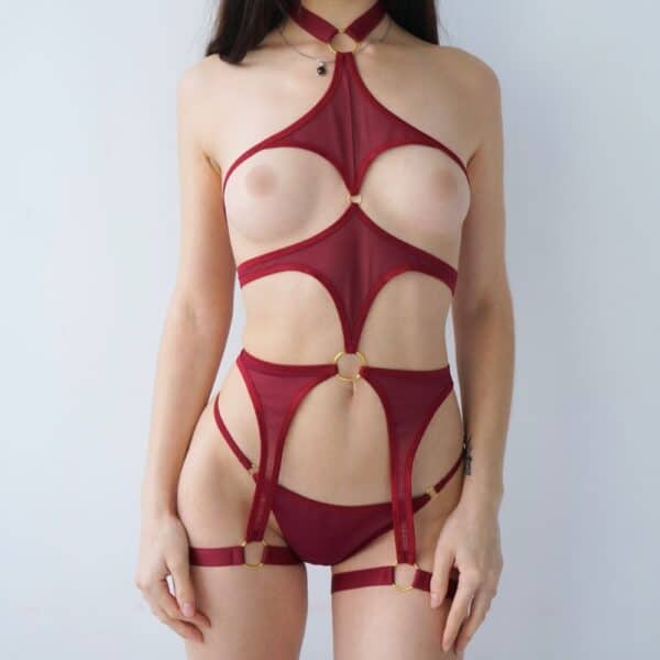 Harnais lingerie rouge avec découpes et anneaux porté par modèle féminin allongé