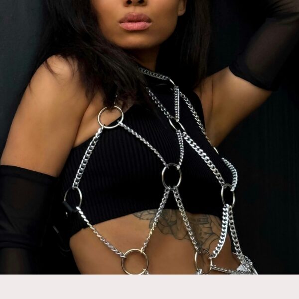 Women's silver chain harness worn over black top, trendy body harness with metal rings