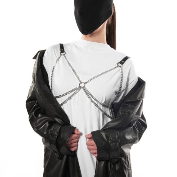 Arnés dorsal de cuero negro con cadenas metálicas sobre una camiseta blanca